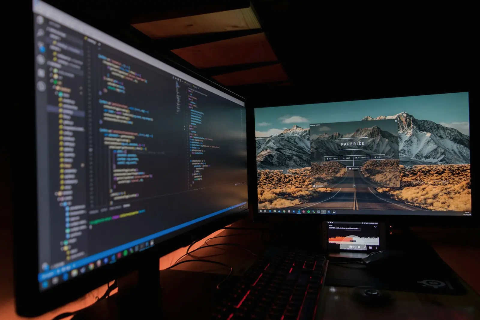 Code open on two large monitors in a dimly lit workspace
