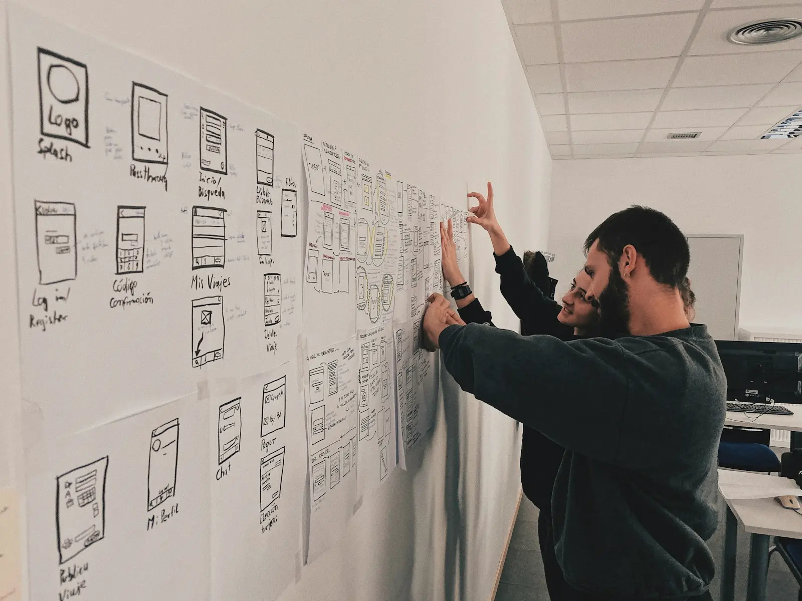 A person standing beside a wall covered in sketches and diagrams